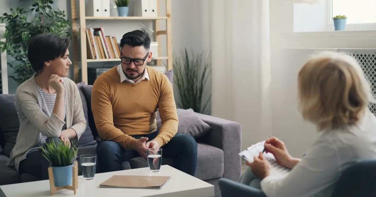 Una pareja conversando con una consejera durante una sesión de orientación familiar
