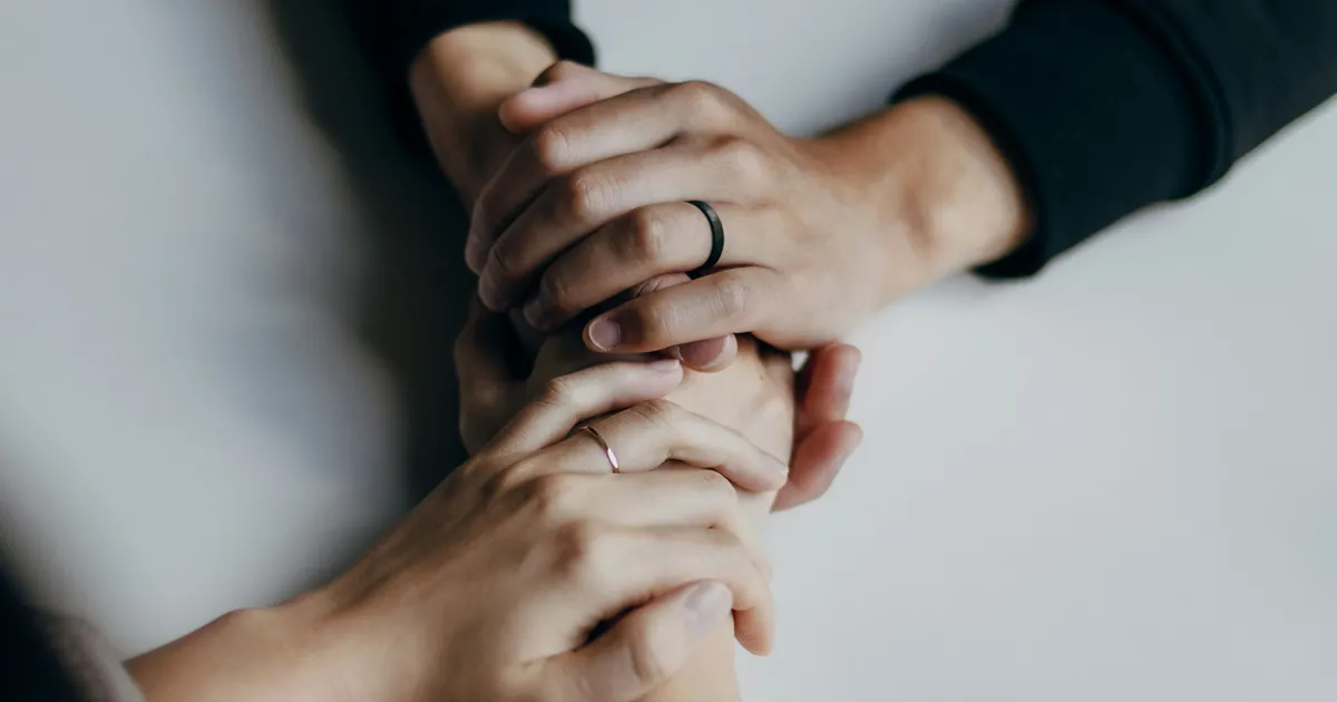 Dos personas tomadas de las manos sobre una mesa, en un gesto de apoyo familiar durante un proceso de recuperación